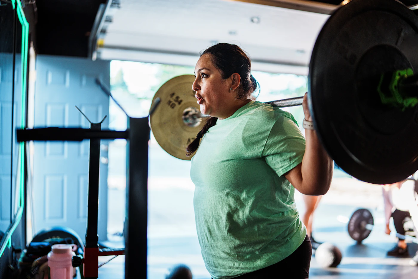 Rubina squatting with a loaded barbell in the gym