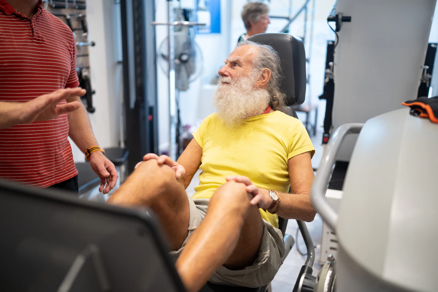 Ken, 71, laughing with his coach between sets on the leg press