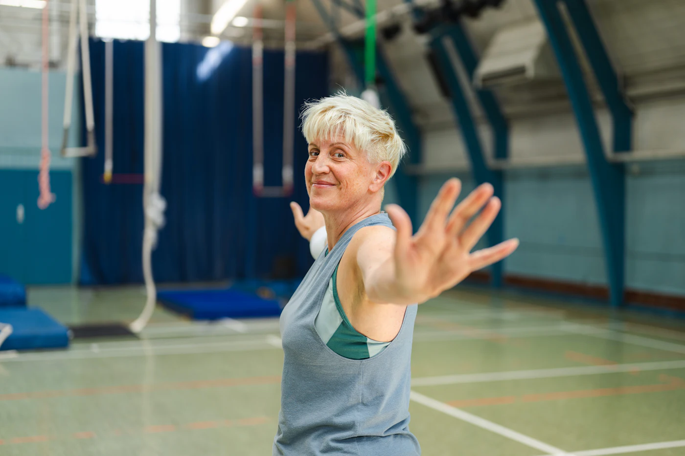 Pat, 71, flexing her arm and grinning in the sports hall